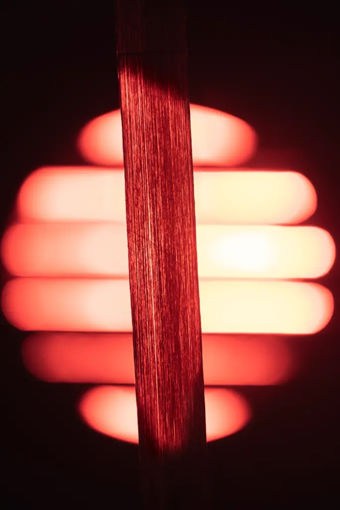 A strip of material is illuminated by a red-orange light source.