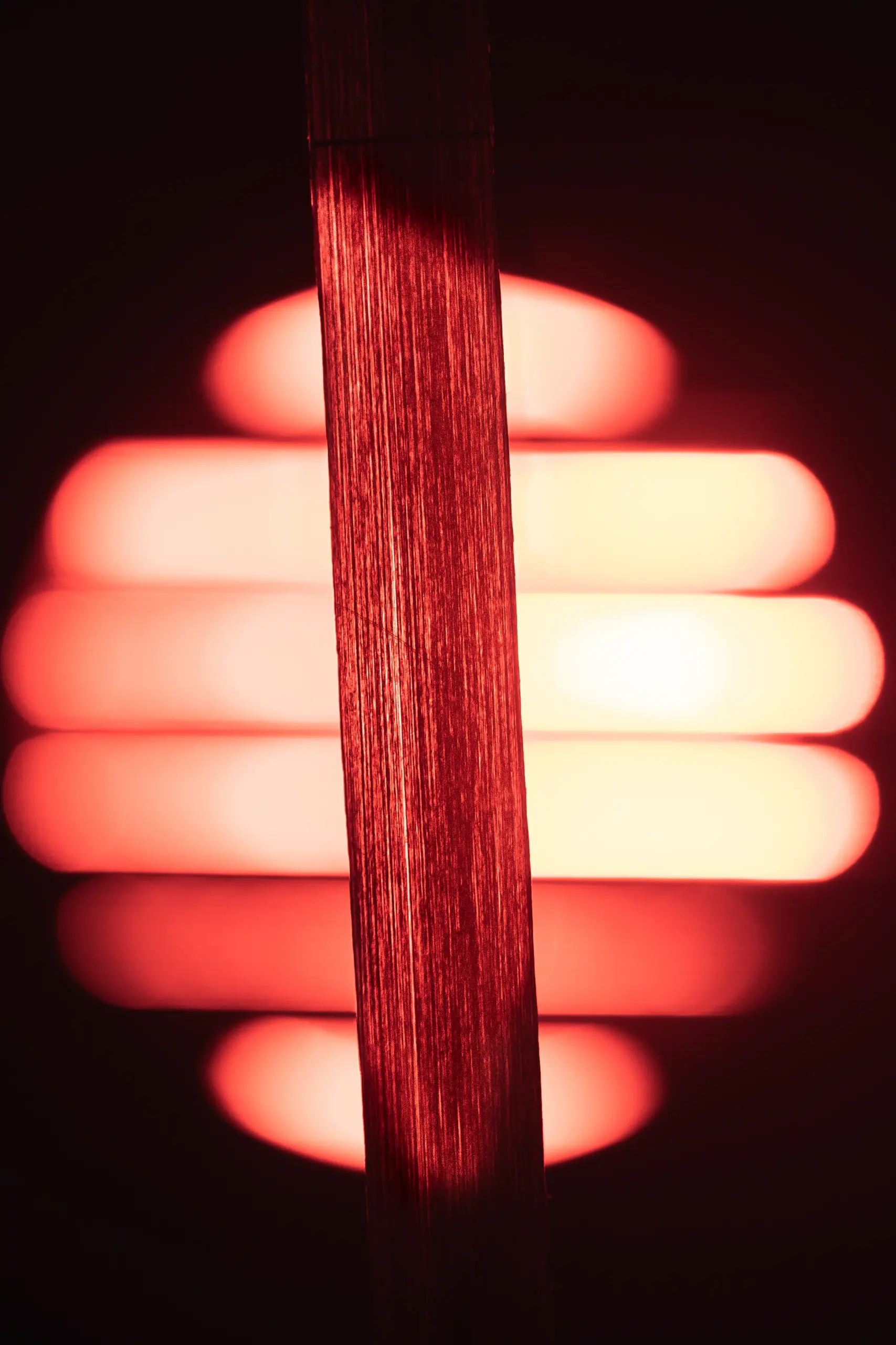 A strip of material is illuminated by a red-orange light source.
