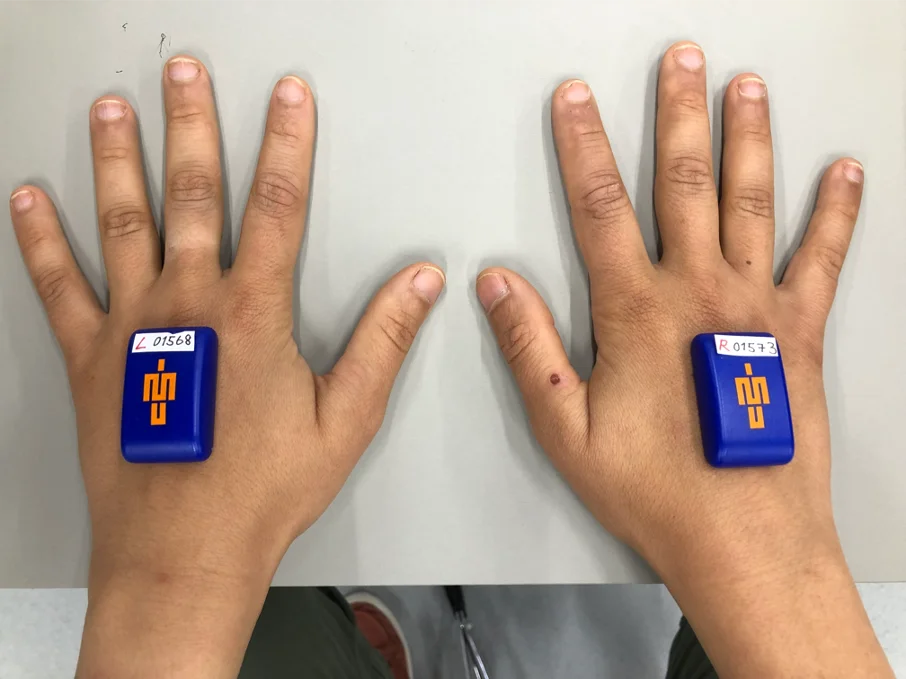 A person's hands with a blue and orange device on them.